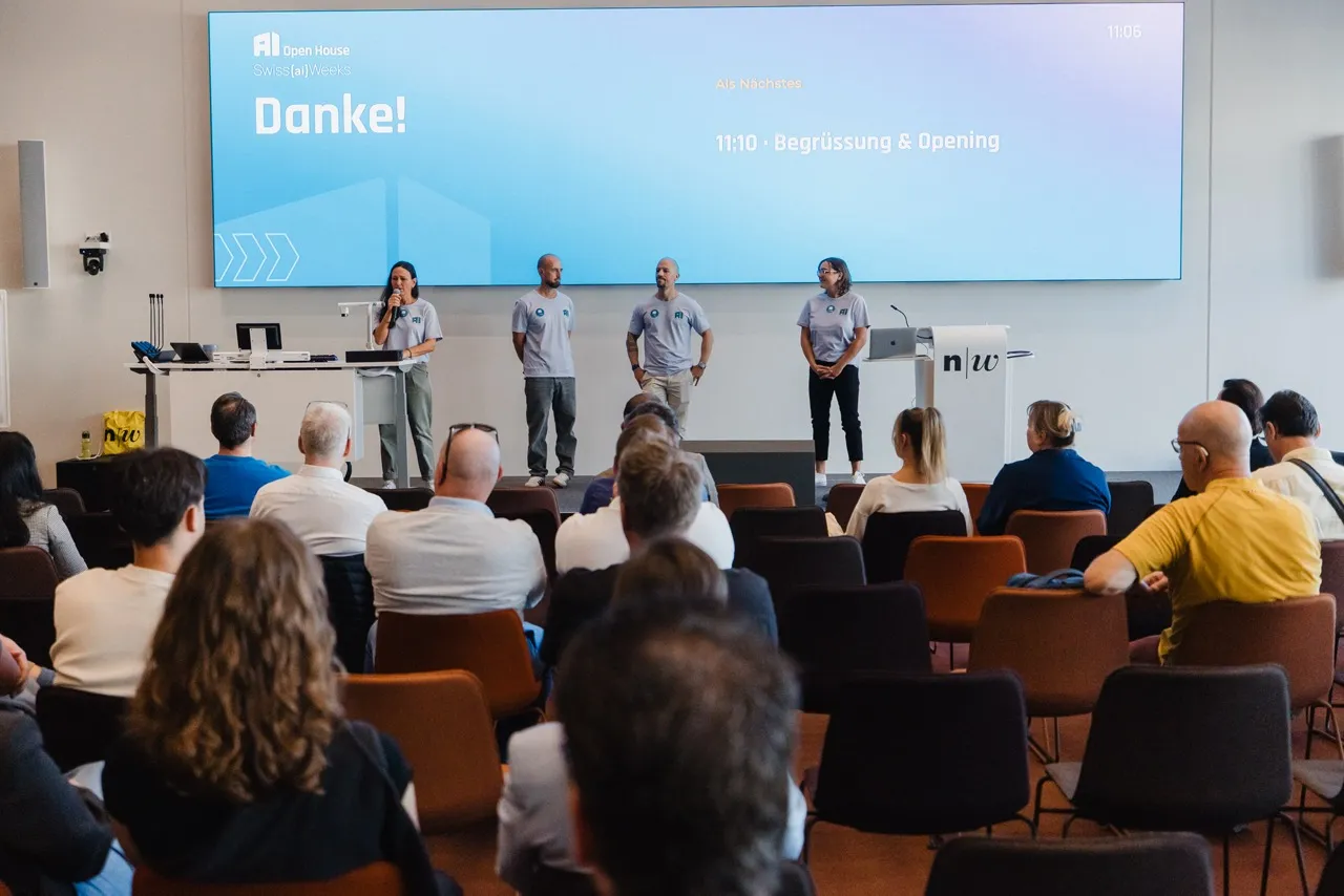 Das Team auf der Bühne der Aula vor vollem Saal